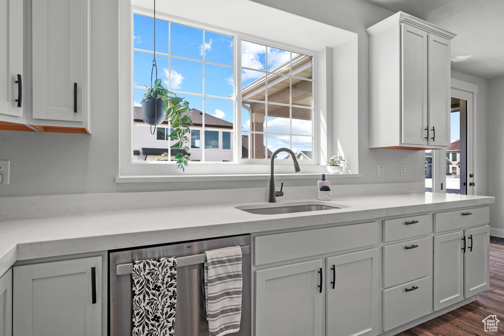 Kitchen featuring white cabinets, dark wood-style flooring, a sink, light countertops, and stainless steel dishwasher
