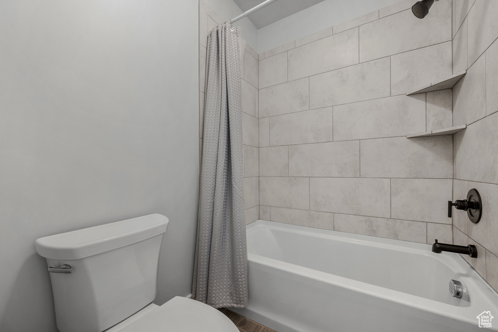 Full bathroom with toilet and shower / tub combo with curtain
