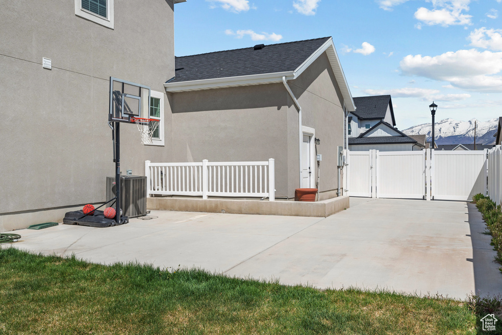 View of side of property with fence, stucco siding, a gate, cooling unit, and a patio