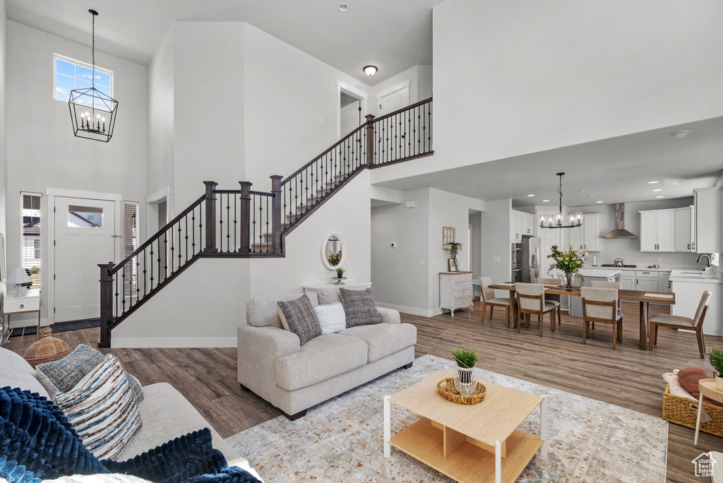 Living area with stairway, a towering ceiling, wood finished floors, and a notable chandelier