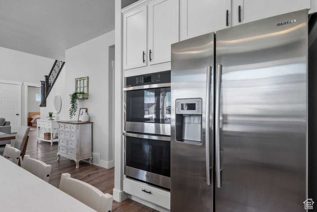 Kitchen with visible vents, dark wood-type flooring, light countertops, white cabinetry, and appliances with stainless steel finishes