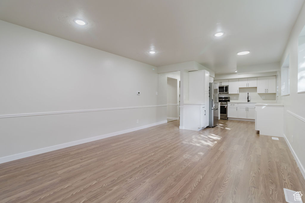 Unfurnished living room with a sink, visible vents, recessed lighting, baseboards, and light wood-style floors