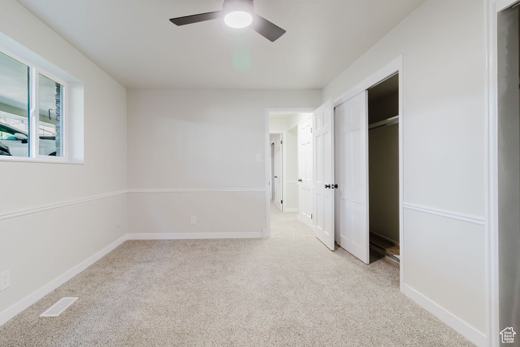 Unfurnished bedroom featuring a ceiling fan, a closet, visible vents, baseboards, and light carpet