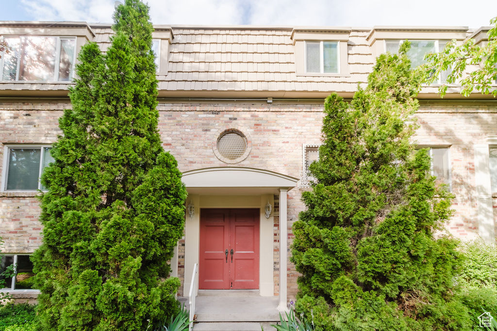 Entrance to property with mansard roof and brick siding