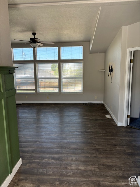 Unfurnished living room with a ceiling fan, baseboards, dark wood finished floors, and a healthy amount of sunlight
