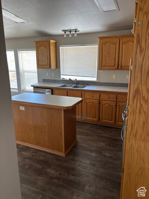Kitchen with a sink, light countertops, dark wood-style floors, and a textured ceiling