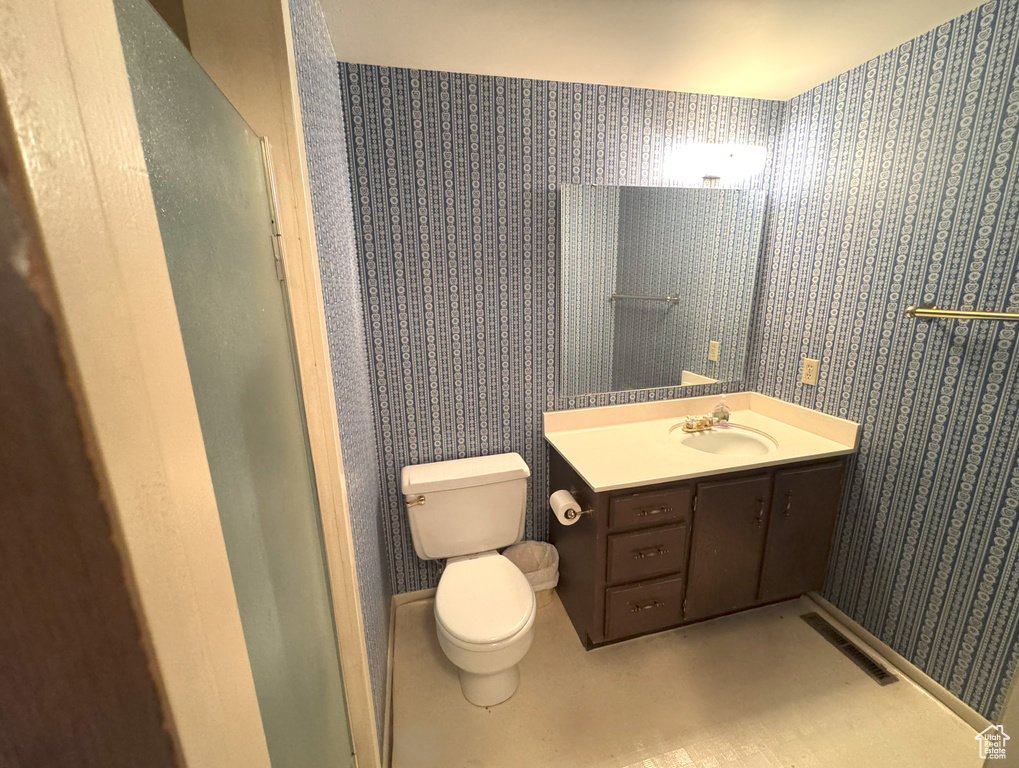Bathroom with vanity, wallpapered walls, toilet, and visible vents