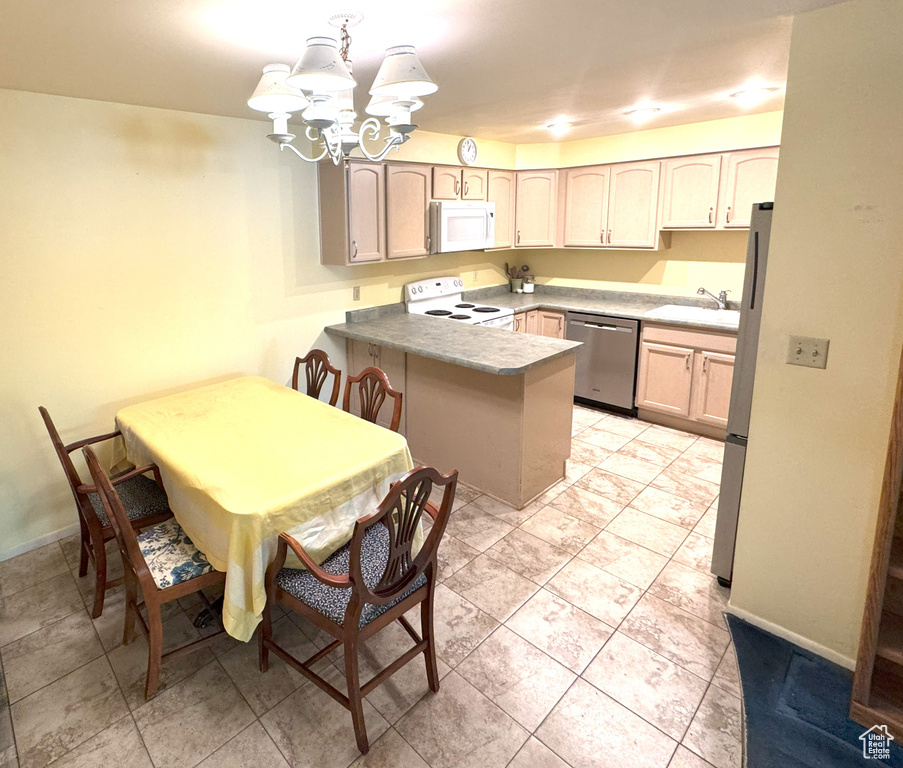 Kitchen with baseboards, a peninsula, a chandelier, and stainless steel appliances