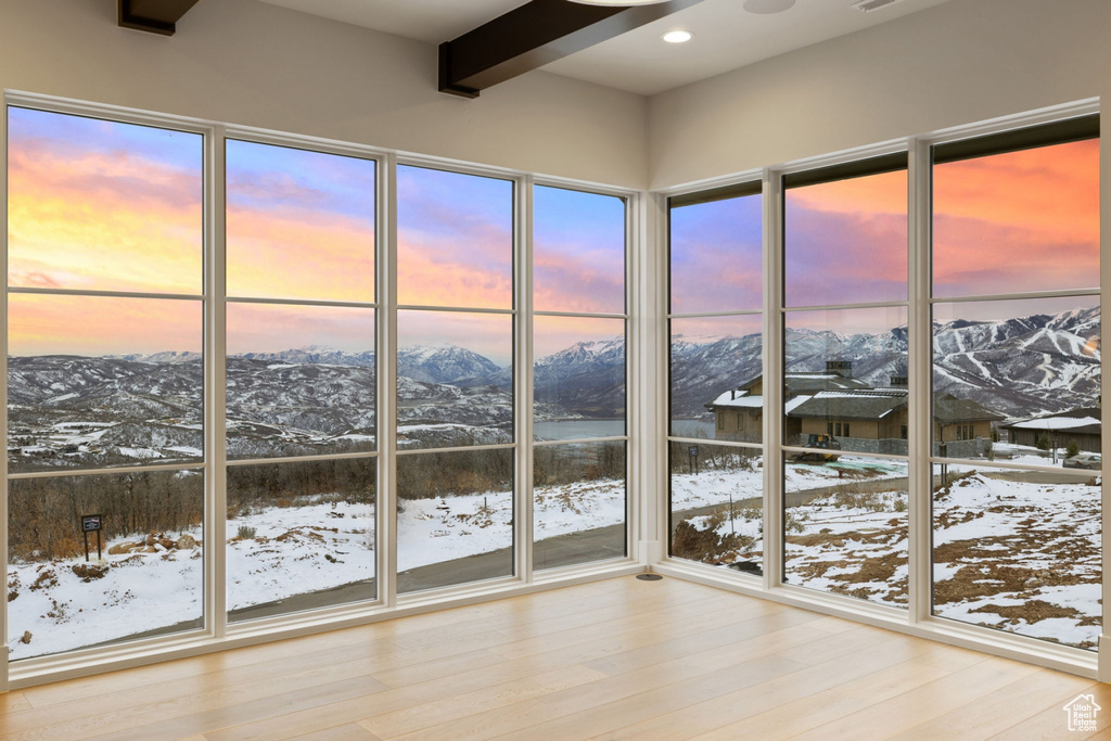 Unfurnished sunroom with a wealth of natural light, a mountain view, and beam ceiling
