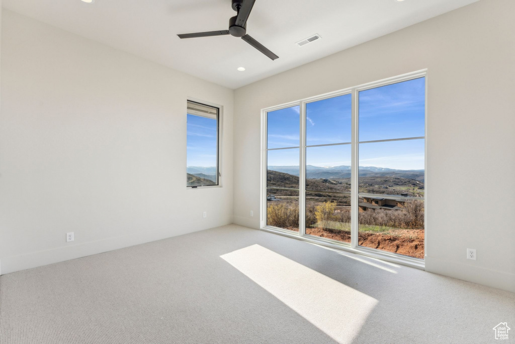 Unfurnished room featuring a mountain view, visible vents, recessed lighting, ceiling fan, and carpet flooring