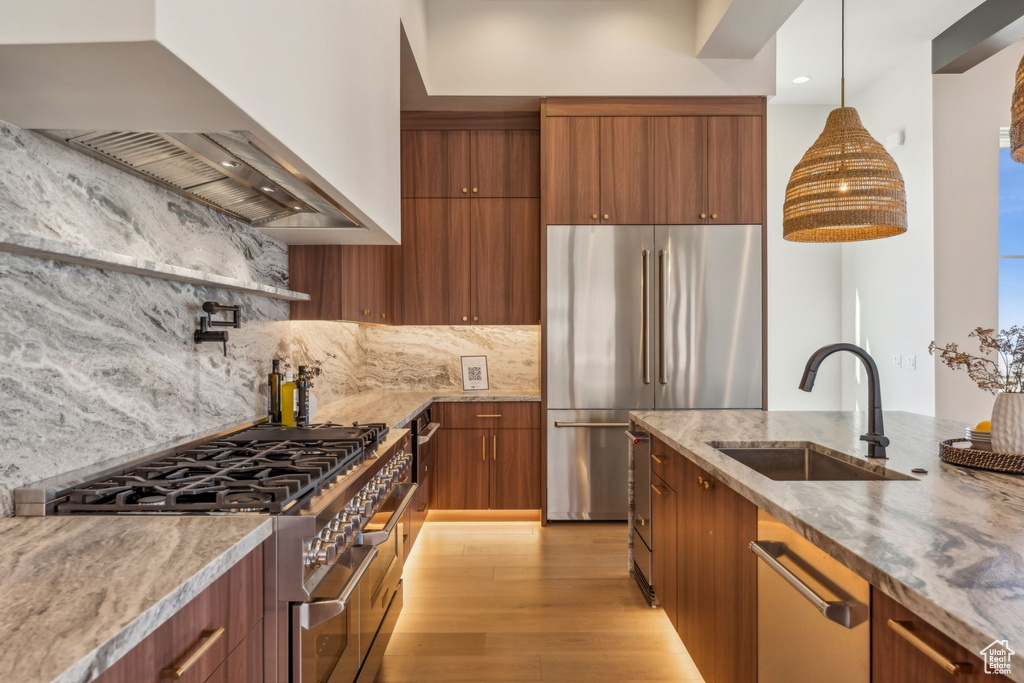 Kitchen featuring wall chimney range hood, stainless steel appliances, a sink, and modern cabinets