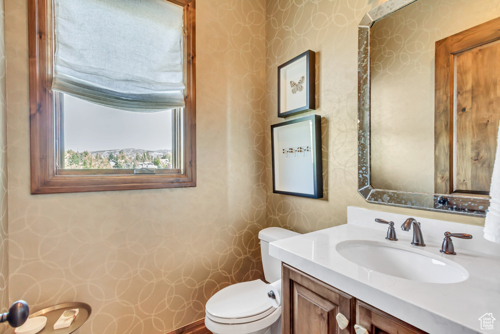 Bathroom featuring vanity, toilet, and wallpapered walls