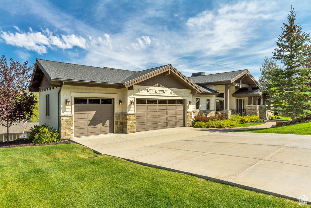 Craftsman inspired home with an attached garage, a front yard, stone siding, and concrete driveway