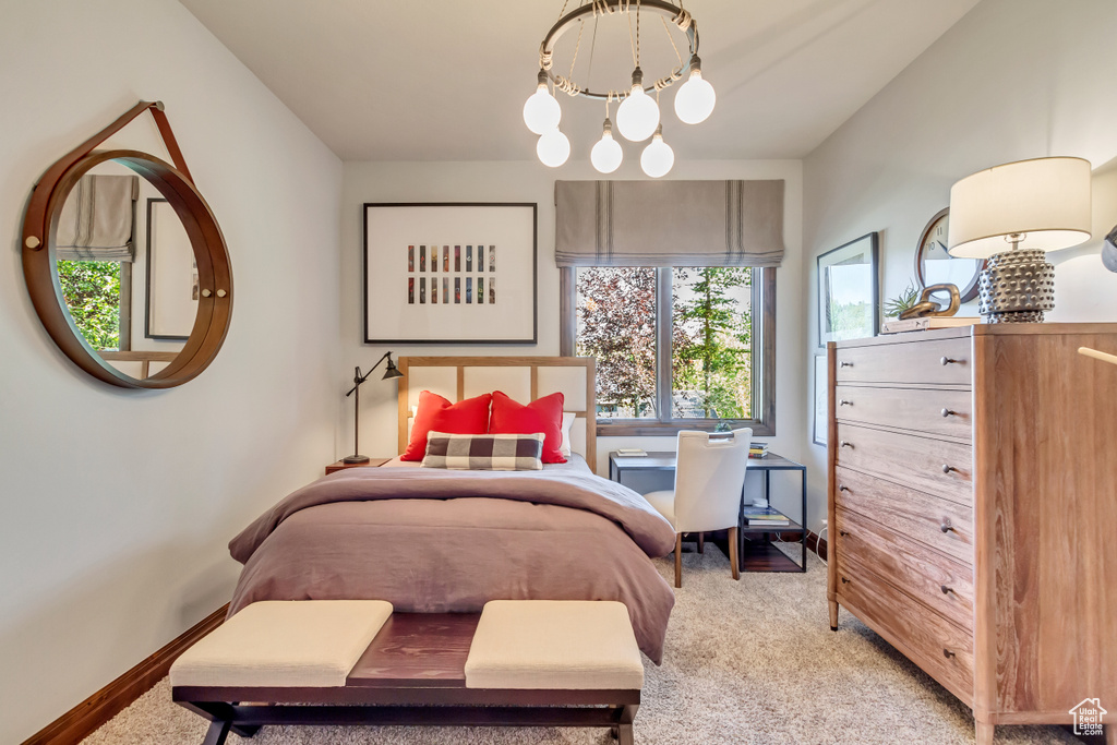 Bedroom featuring a notable chandelier, baseboards, and light colored carpet