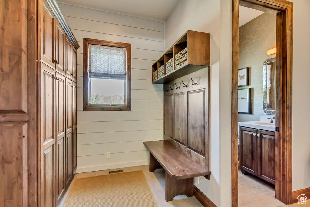Mudroom featuring wooden walls, baseboards, a sink, and visible vents