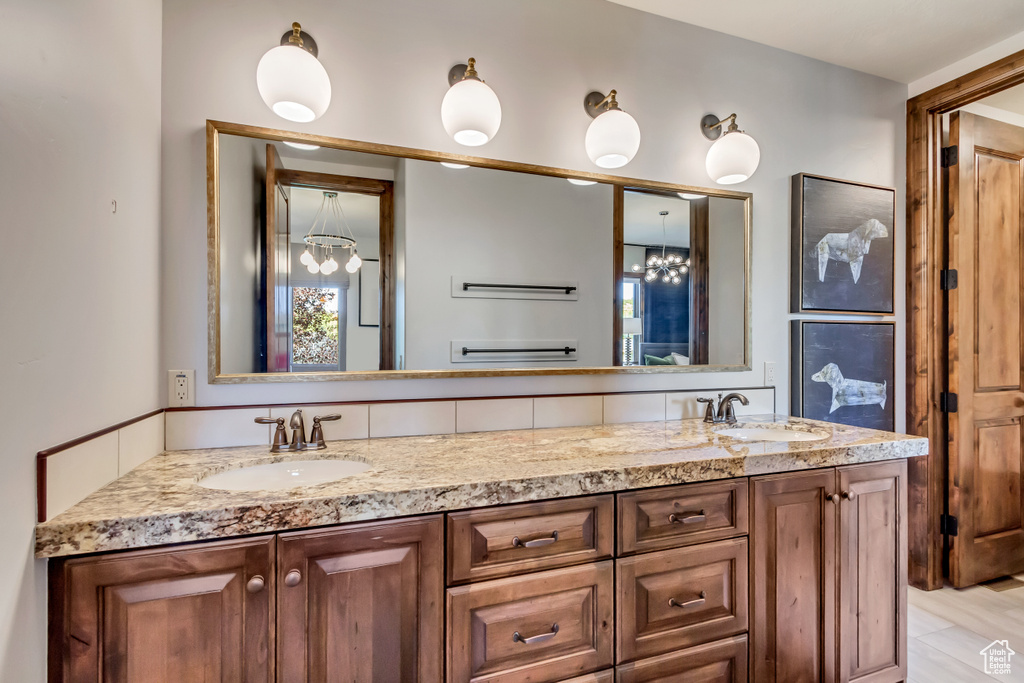 Full bath with a sink, double vanity, and a chandelier
