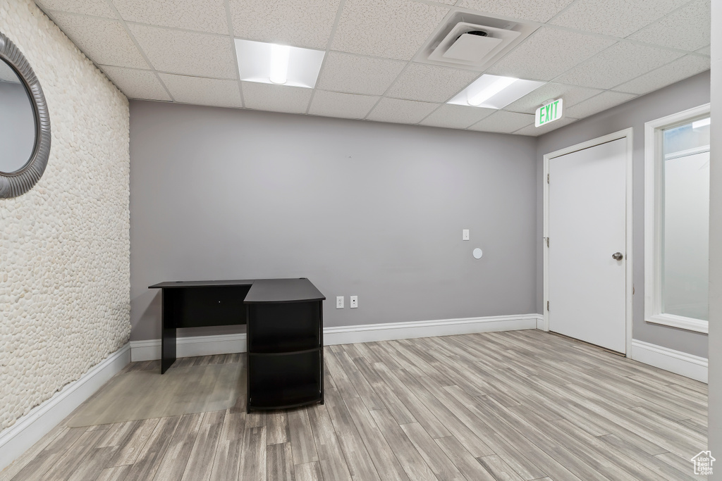 Interior space with baseboards, a drop ceiling, visible vents, and wood finished floors