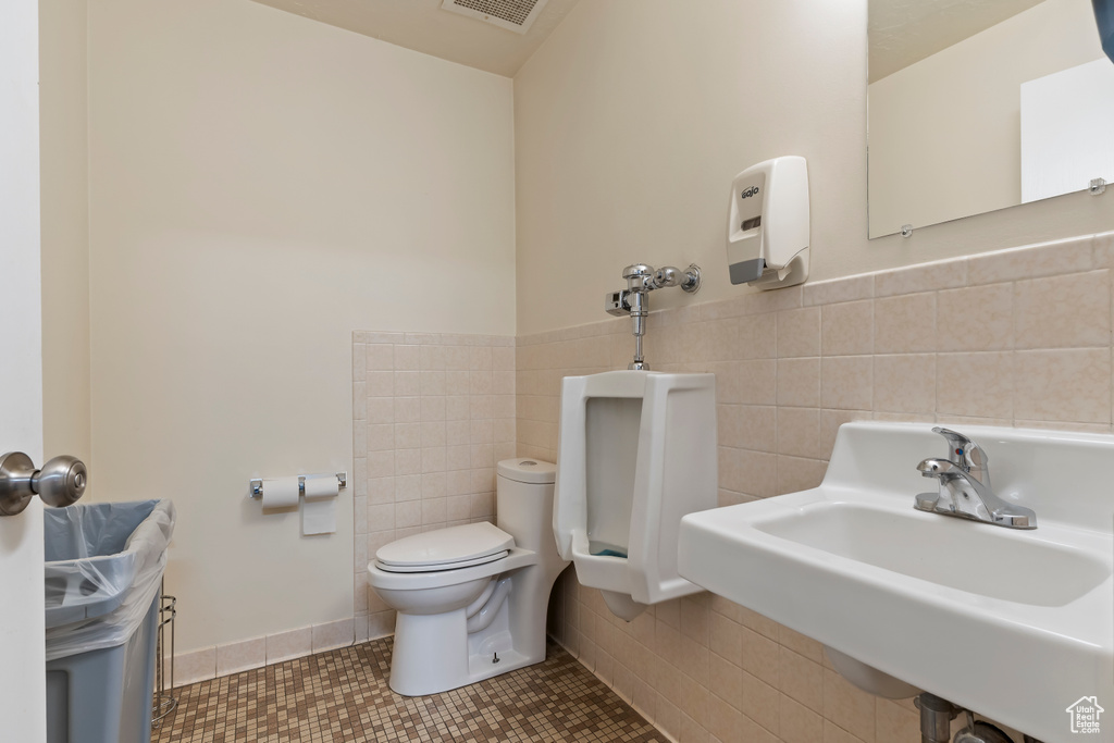 Half bathroom with a sink, tile walls, toilet, visible vents, and tile patterned flooring