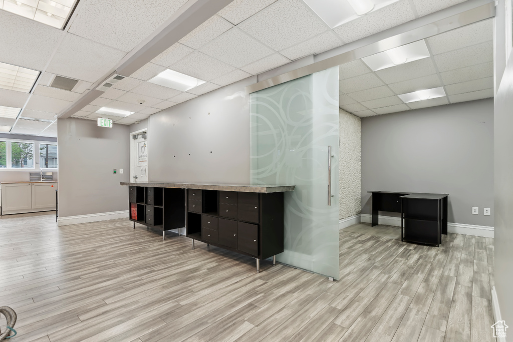 Interior space featuring a drop ceiling, wood finished floors, and baseboards