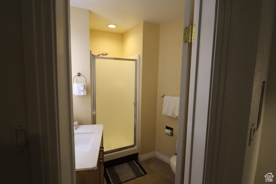 Full bathroom featuring vanity, toilet, baseboards, and a shower stall