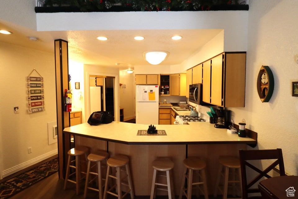 Kitchen with stainless steel microwave, a peninsula, freestanding refrigerator, recessed lighting, and range with gas cooktop