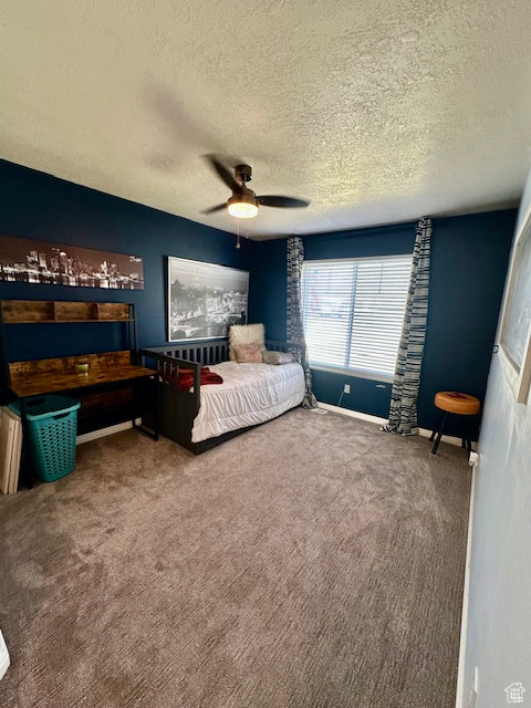 Bedroom with a textured ceiling, carpet, ceiling fan, and baseboards