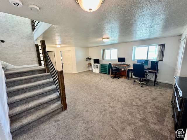 Home office featuring a textured ceiling, carpet, and baseboards