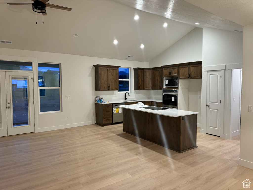 Kitchen with a center island, visible vents, a sink, dark brown cabinetry, and stainless steel appliances