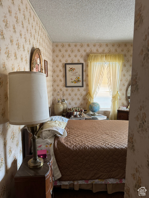 Bedroom with crown molding, wallpapered walls, and a textured ceiling