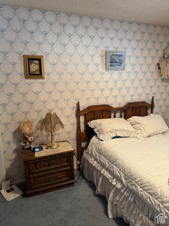 Carpeted bedroom featuring wallpapered walls and a textured ceiling