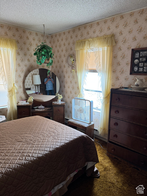 Carpeted bedroom with wallpapered walls and a textured ceiling