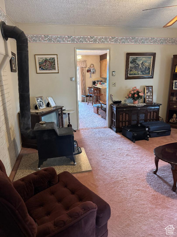 Living room with a wood stove, a textured ceiling, carpet, and a ceiling fan