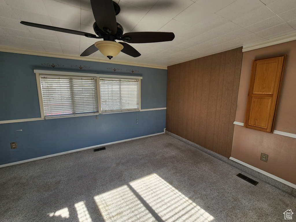 Empty room featuring crown molding, a ceiling fan, and visible vents