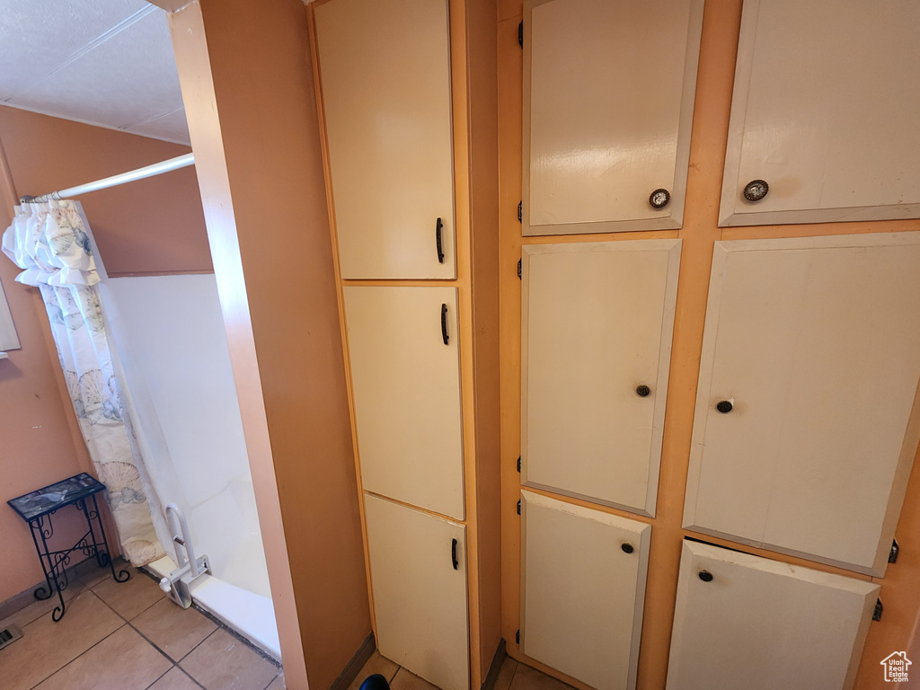 Interior space featuring tile patterned flooring, curtained shower, and visible vents