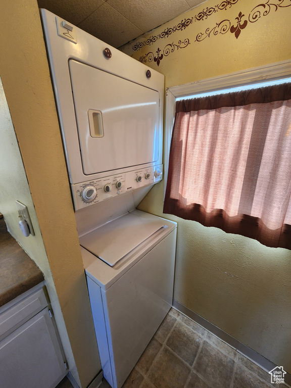 Washroom with laundry area, stacked washer / dryer, and stone finish floor
