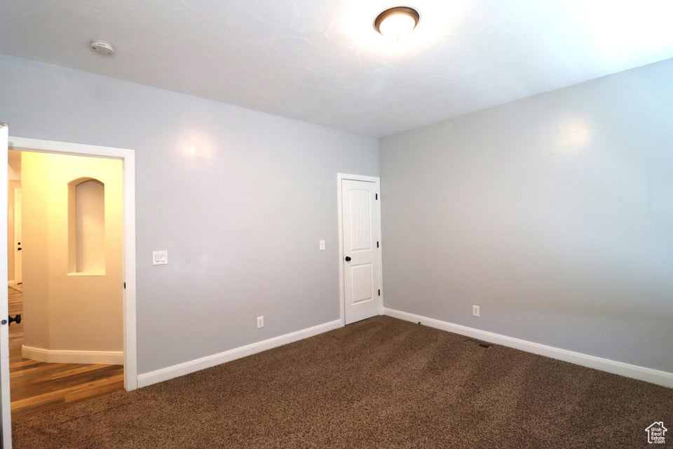 Empty room with dark colored carpet and baseboards