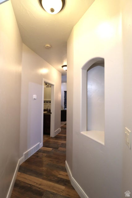 Hall with visible vents, arched walkways, and dark wood-style floors