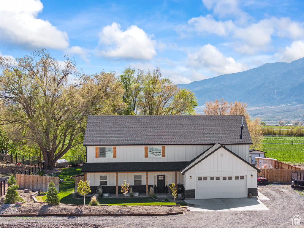 Modern farmhouse style home with roof with shingles, fence, a mountain view, driveway, and a garage