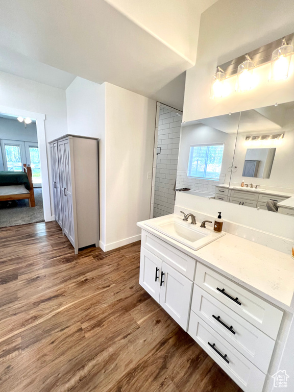 Ensuite bathroom featuring a wealth of natural light, baseboards, and wood finished floors