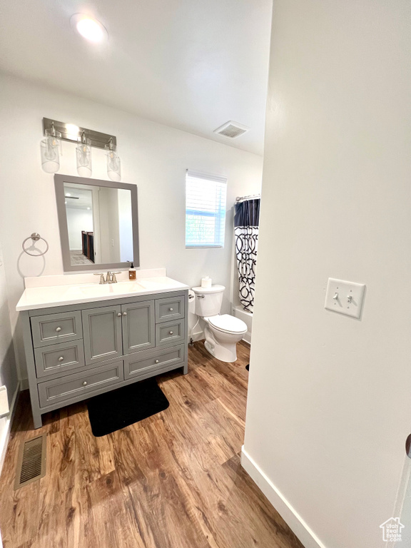 Full bathroom featuring toilet, wood finished floors, visible vents, baseboards, and vanity