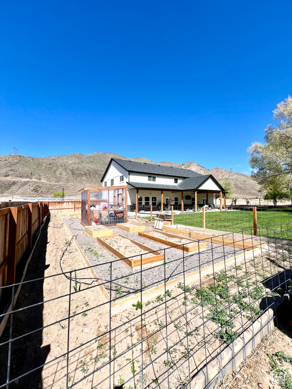 Rear view of house with fence, stucco siding, and a mountain view