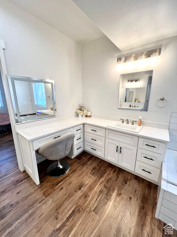 Full bathroom with wood finished floors, vanity, and a tub to relax in