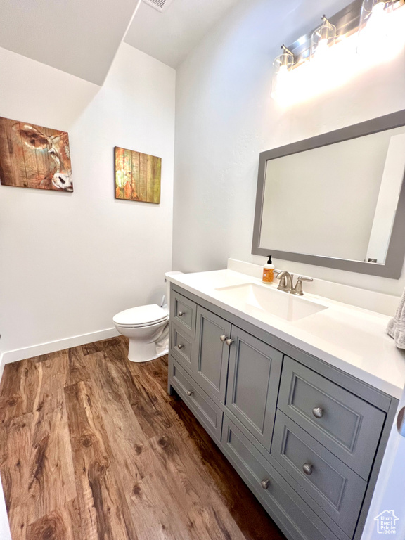Bathroom with vanity, toilet, baseboards, and wood finished floors