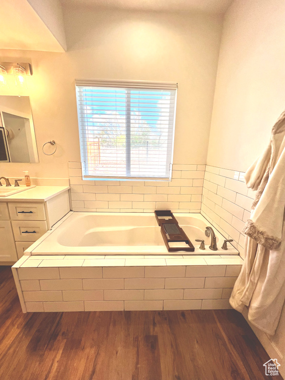 Bathroom with a bath, plenty of natural light, wood finished floors, and vanity