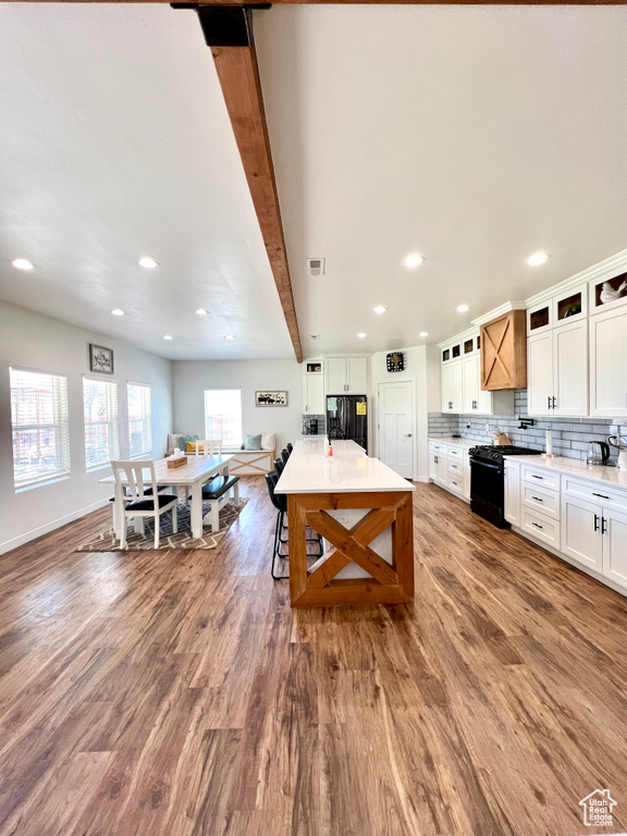 Kitchen featuring glass insert cabinets, wood finished floors, white cabinetry, black appliances, and recessed lighting