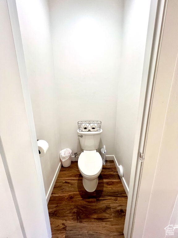 Bathroom with toilet, baseboards, and wood finished floors