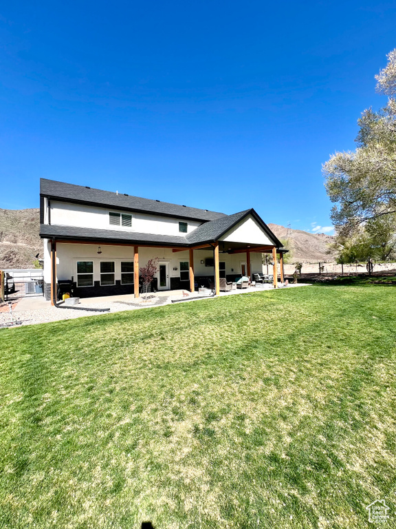 Rear view of property with a yard, a mountain view, a patio area, and fence