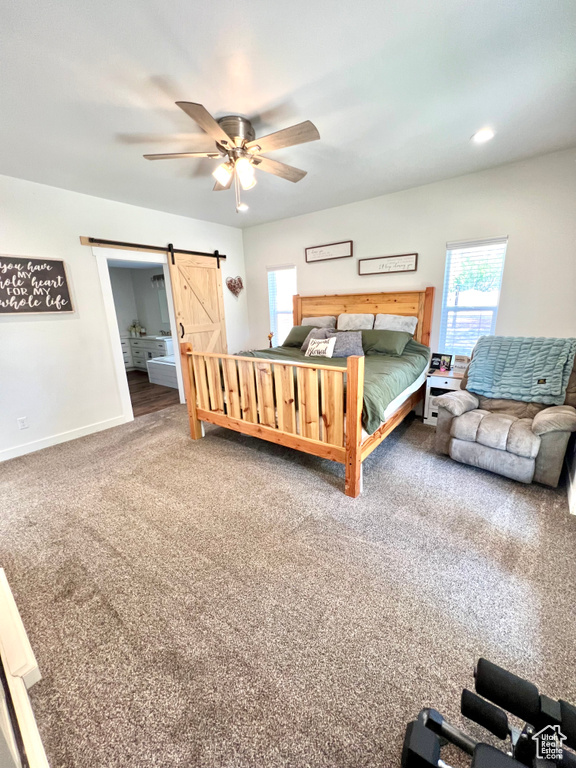 Carpeted bedroom featuring a ceiling fan, a barn door, and baseboards