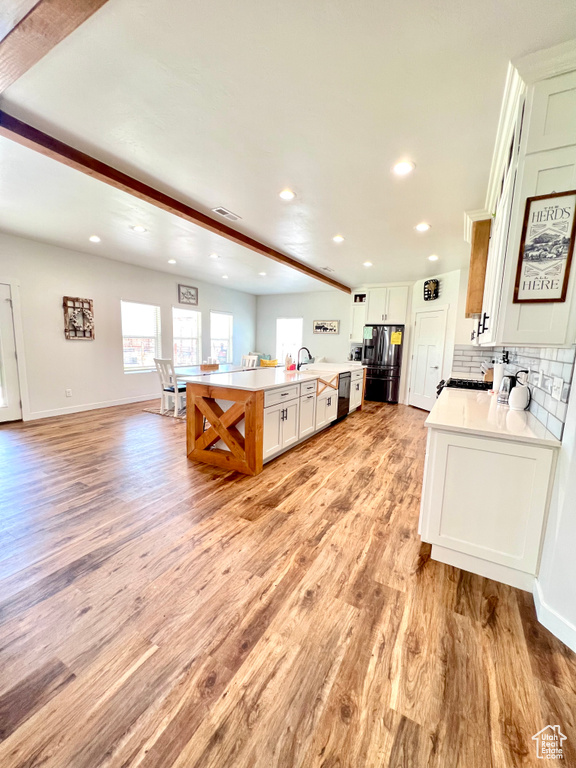 Kitchen with dishwashing machine, light countertops, a healthy amount of sunlight, and stainless steel refrigerator with ice dispenser