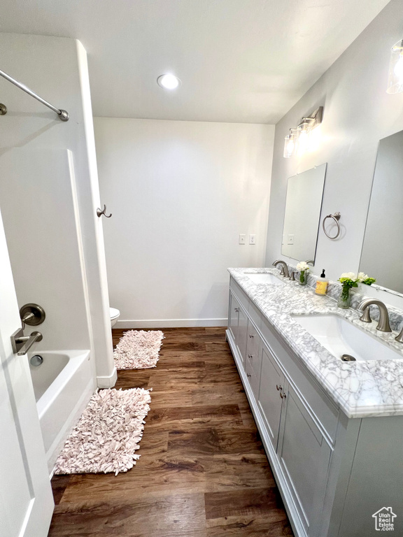 Full bathroom featuring double vanity, toilet, wood finished floors, and a sink